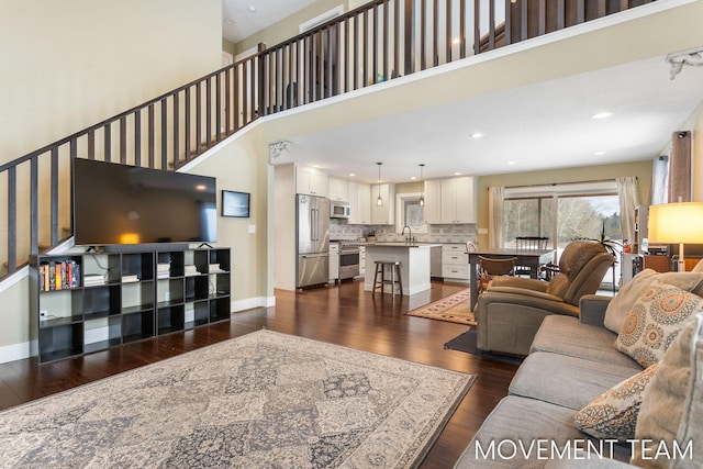 living room with a towering ceiling and dark wood-type flooring