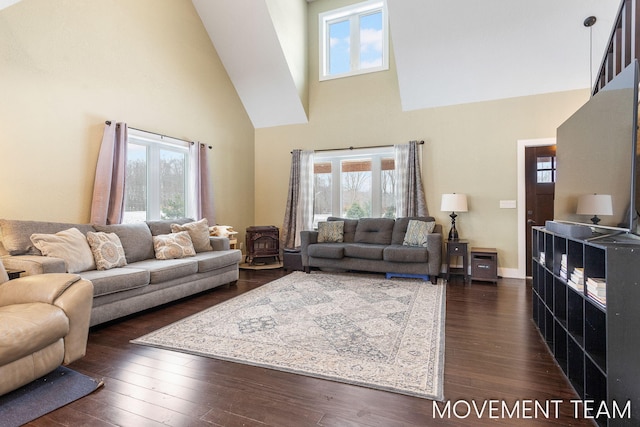 living room with a high ceiling, a wood stove, and dark wood-type flooring