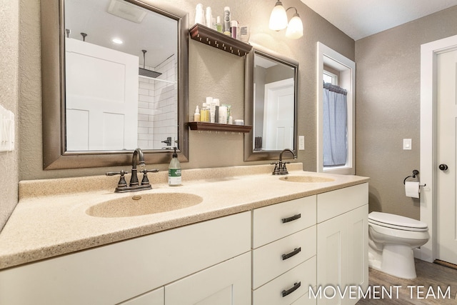 bathroom with walk in shower, vanity, and toilet