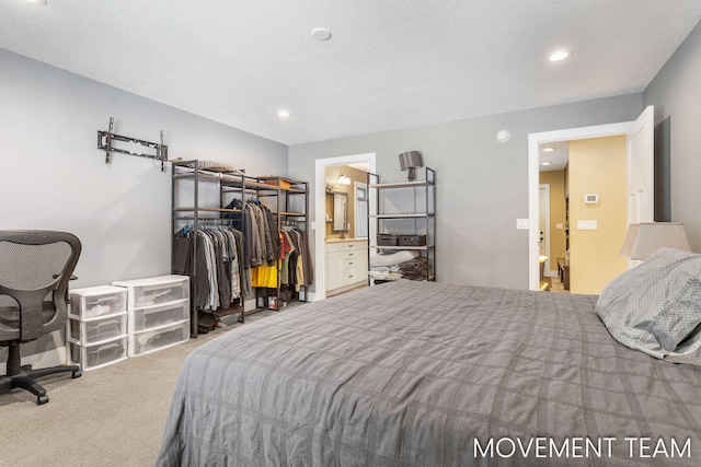 bedroom with carpet flooring, a textured ceiling, ensuite bathroom, and a closet