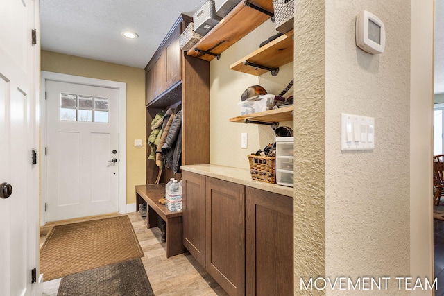 mudroom with light hardwood / wood-style floors and a textured ceiling