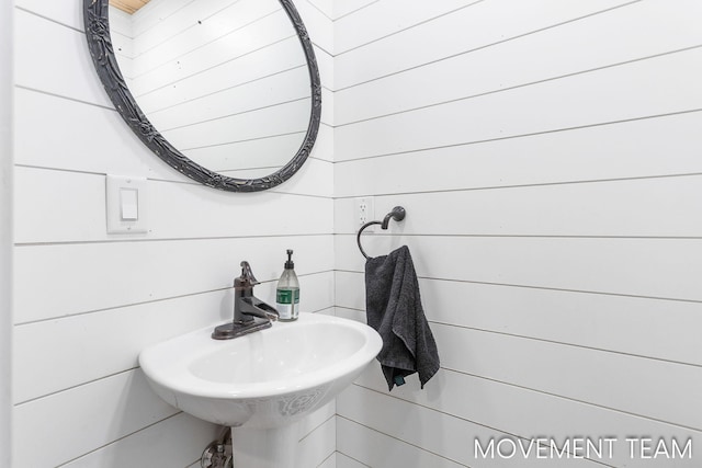 bathroom with wood walls and sink