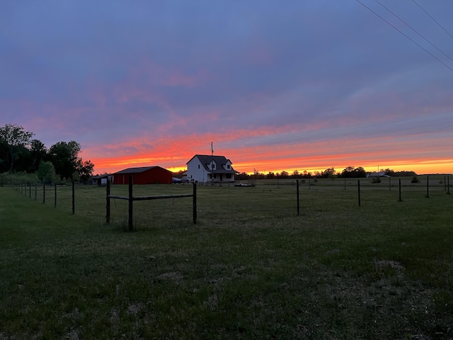 yard at dusk featuring a rural view