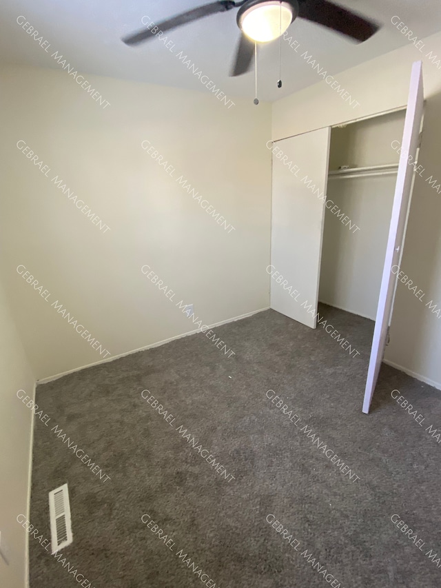 unfurnished bedroom featuring ceiling fan, a closet, and dark colored carpet