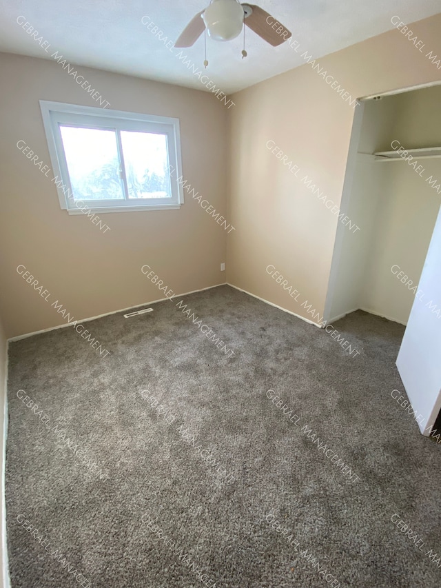 unfurnished bedroom with dark carpet, a closet, and ceiling fan