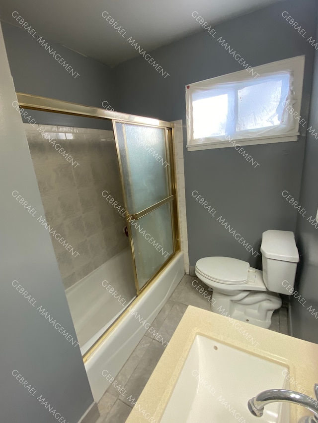 bathroom featuring toilet, combined bath / shower with glass door, and tile patterned floors