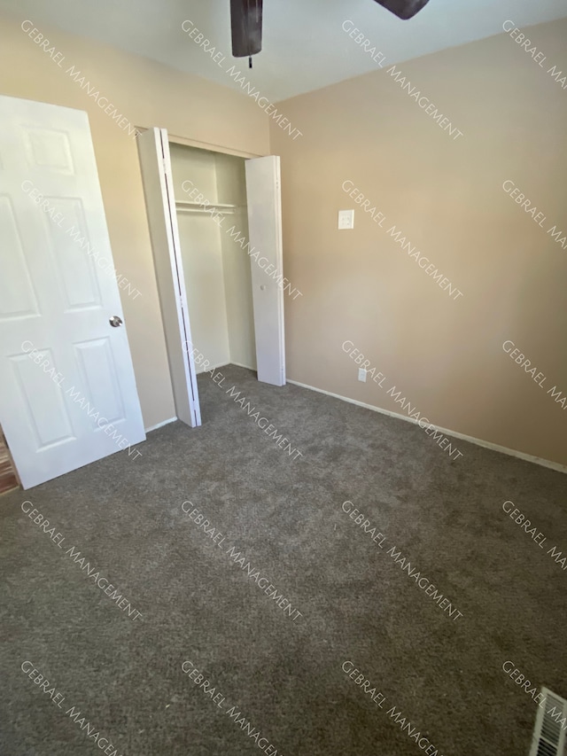 unfurnished bedroom featuring dark carpet, a closet, and ceiling fan