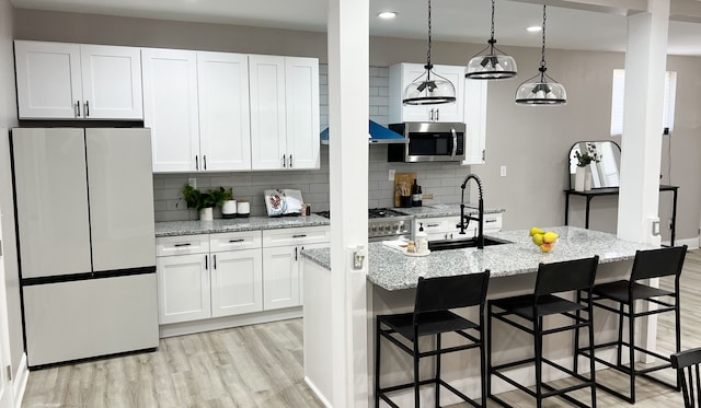 kitchen with decorative light fixtures, light stone countertops, white cabinetry, and fridge