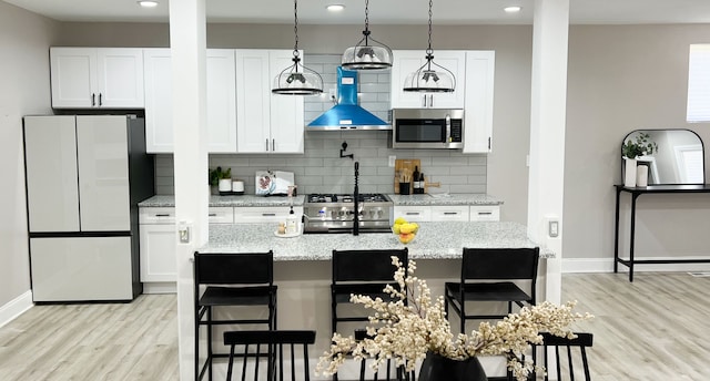 kitchen featuring white cabinetry, ventilation hood, light stone countertops, and appliances with stainless steel finishes