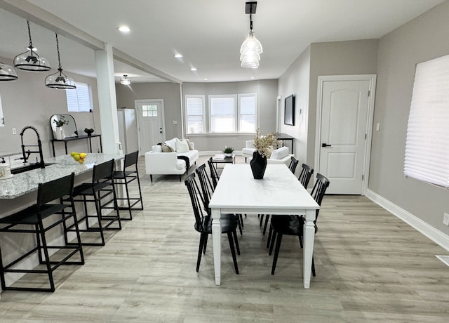 dining space with light wood-type flooring and sink