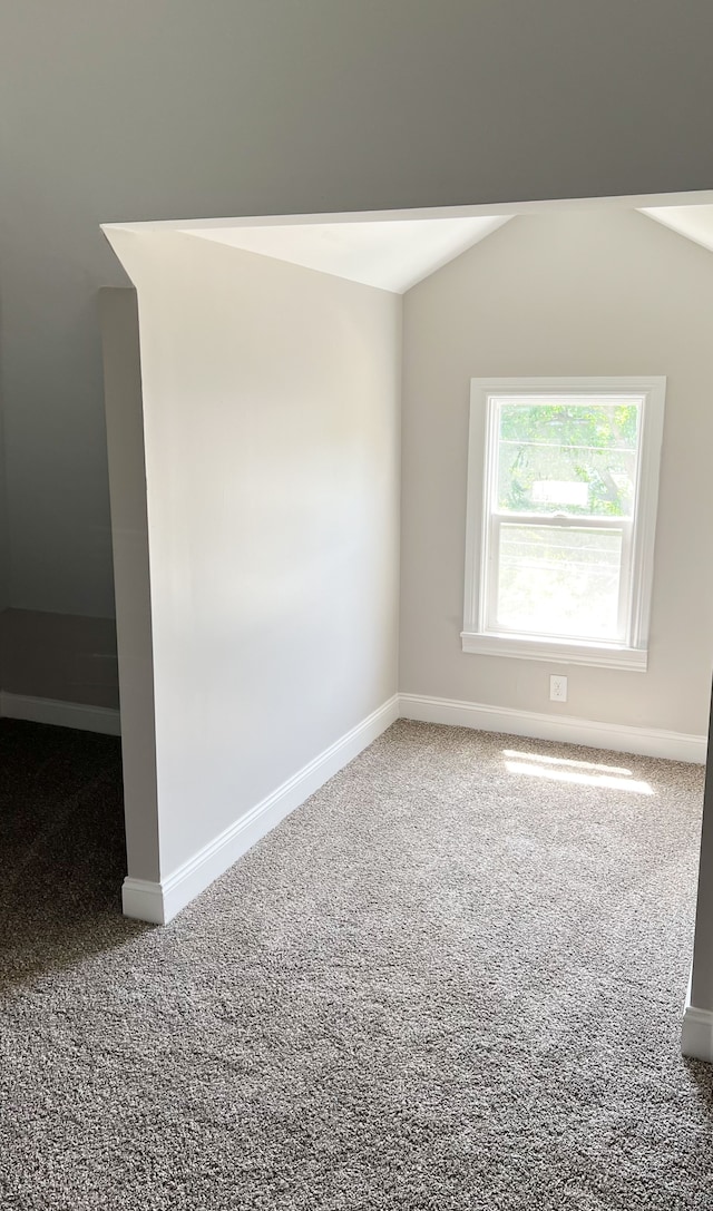 carpeted spare room with vaulted ceiling