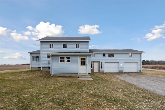 back of property with a garage and a lawn