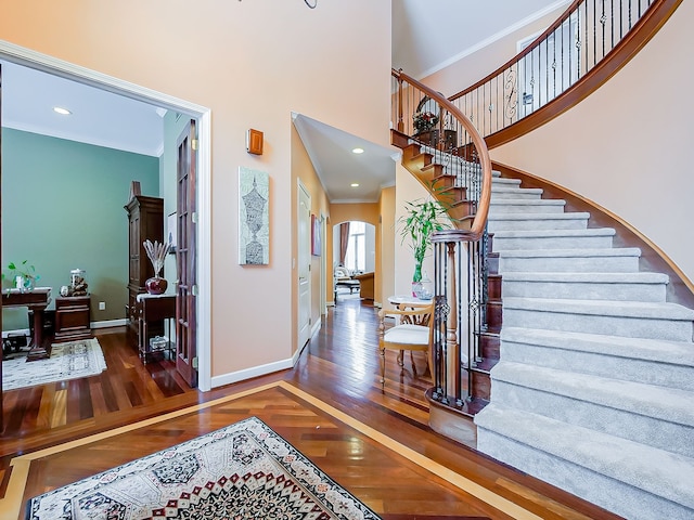 entrance foyer featuring a high ceiling, dark hardwood / wood-style flooring, and ornamental molding