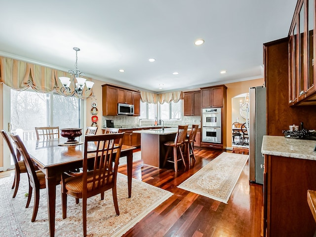 dining area with dark wood-type flooring, a notable chandelier, and ornamental molding