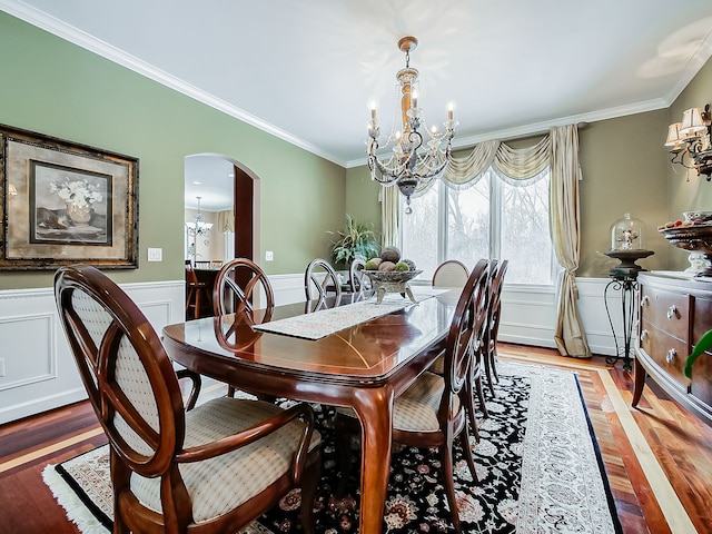 dining room with a wainscoted wall, arched walkways, and an inviting chandelier