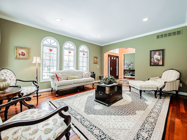 living room featuring dark wood-style floors, visible vents, crown molding, and arched walkways