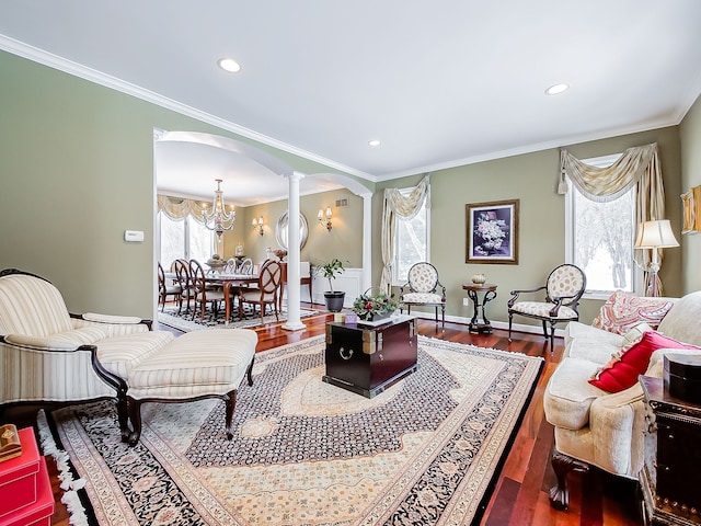 living room with ornate columns, hardwood / wood-style floors, a chandelier, and ornamental molding