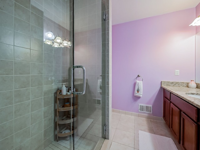 bathroom featuring vanity, baseboards, tile patterned floors, a stall shower, and visible vents