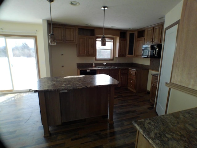 kitchen with brown cabinetry, dark wood finished floors, black microwave, pendant lighting, and a sink