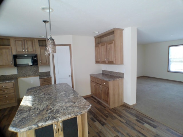 kitchen featuring hanging light fixtures, a kitchen island, black microwave, and dark wood-type flooring