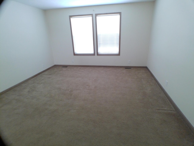 unfurnished room featuring light carpet and baseboards