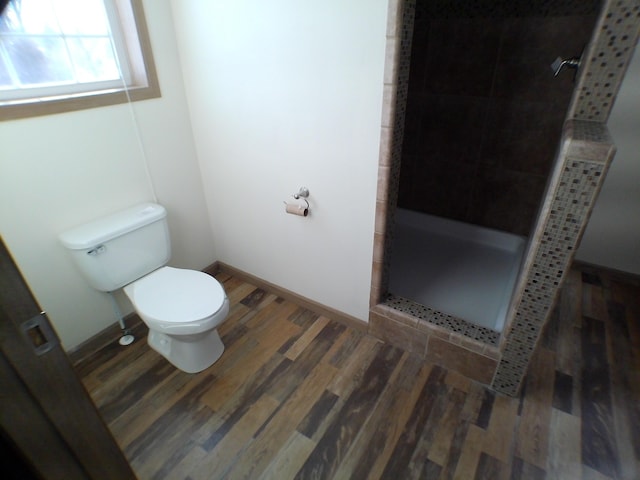 full bathroom with baseboards, wood finished floors, toilet, and a shower stall