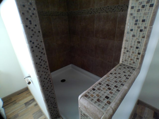 bathroom featuring tiled shower, wood finished floors, and baseboards