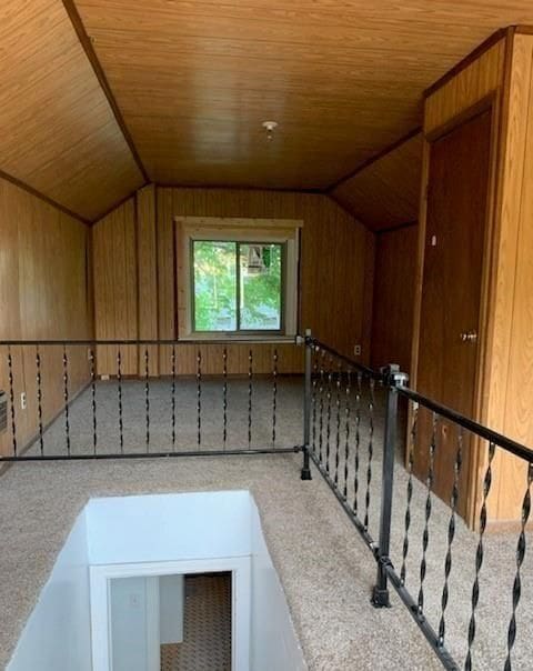 bonus room with wood walls and vaulted ceiling