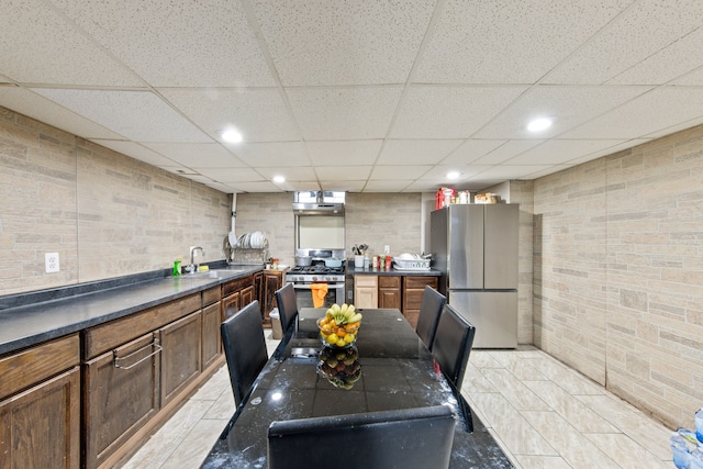 kitchen with light tile patterned flooring, stainless steel appliances, a drop ceiling, and sink