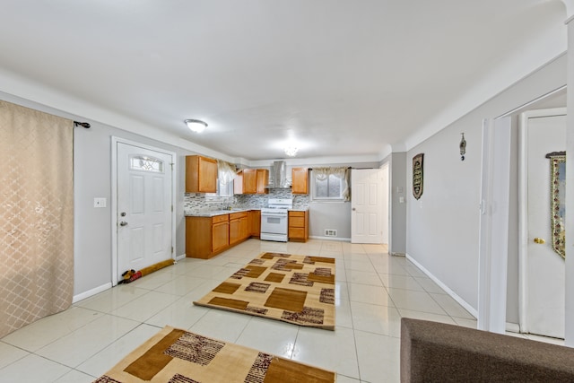 kitchen with light tile patterned flooring, white range oven, wall chimney exhaust hood, and tasteful backsplash