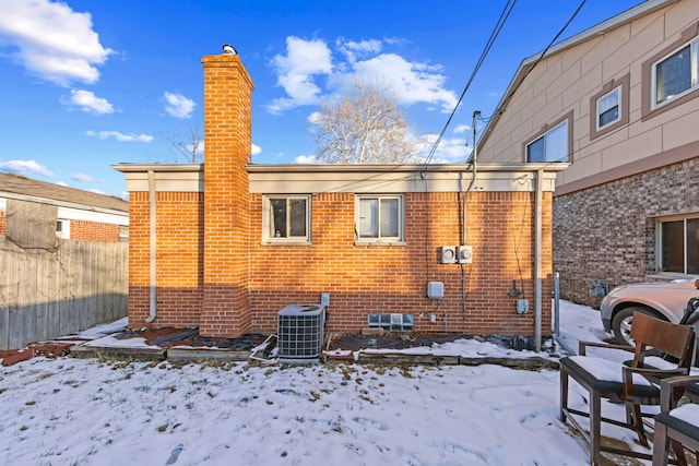 snow covered rear of property featuring central air condition unit