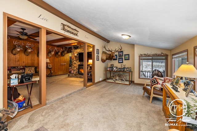 sitting room featuring ceiling fan, wood walls, carpet, and lofted ceiling