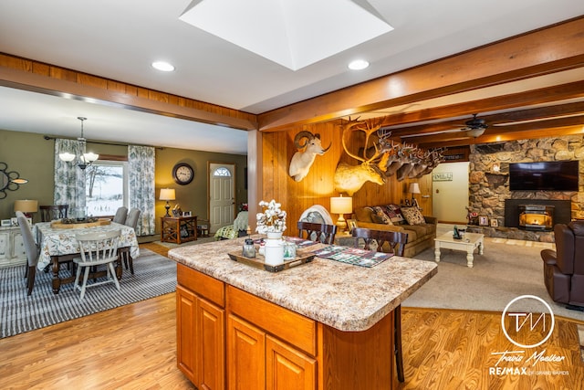 kitchen featuring light stone countertops, a skylight, ceiling fan with notable chandelier, a kitchen island, and hanging light fixtures