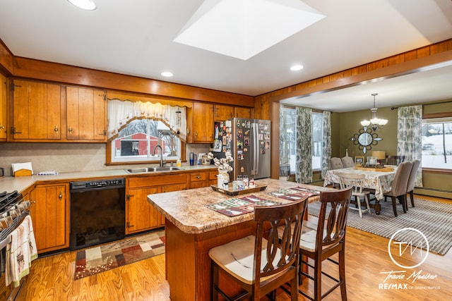 kitchen with stainless steel appliances, sink, a notable chandelier, a kitchen island, and hanging light fixtures