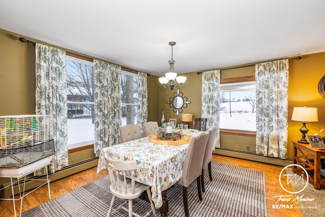 dining space featuring light hardwood / wood-style floors, a healthy amount of sunlight, a notable chandelier, and a baseboard heating unit