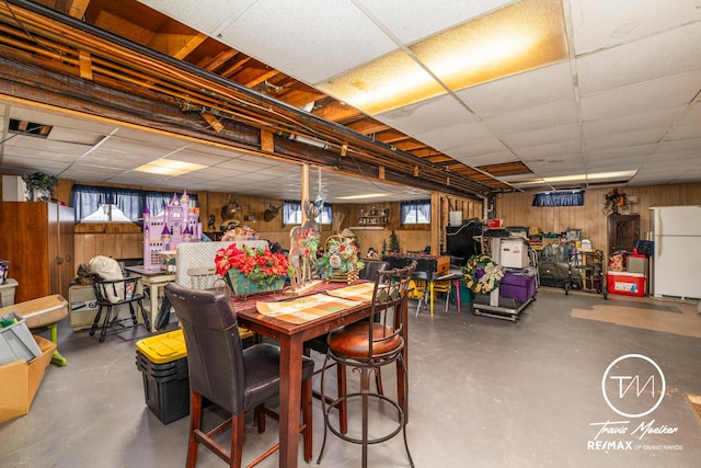 dining space with a paneled ceiling, plenty of natural light, wood walls, and concrete floors