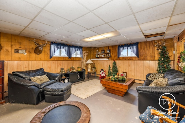 living room featuring concrete flooring, a paneled ceiling, plenty of natural light, and wooden walls