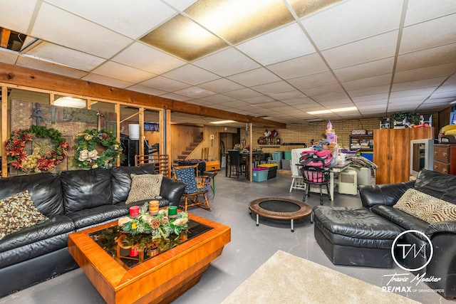 living room featuring a paneled ceiling and concrete floors