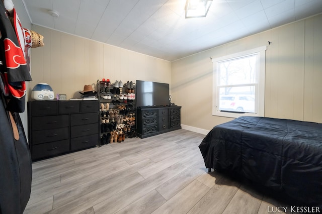 bedroom with light hardwood / wood-style floors and wood walls