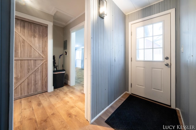 doorway with wood walls, ornamental molding, and light hardwood / wood-style flooring