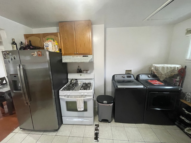 kitchen featuring white range with gas stovetop, stainless steel fridge with ice dispenser, light tile patterned floors, and washer and clothes dryer