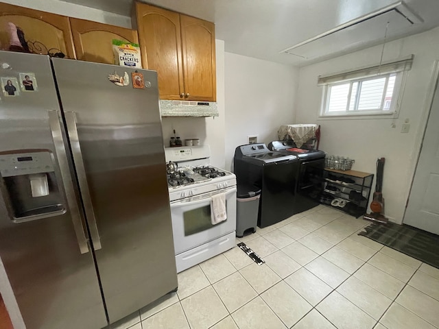 kitchen featuring white gas range oven, stainless steel fridge, washing machine and dryer, light tile patterned floors, and tasteful backsplash