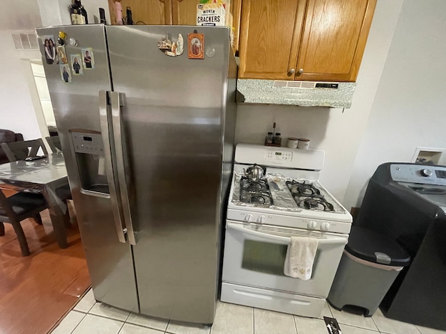 kitchen with stainless steel fridge, light tile patterned floors, and white gas range oven