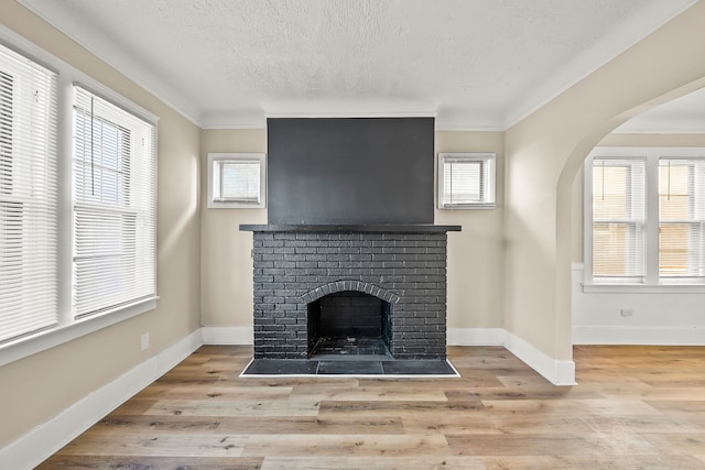 unfurnished living room with a brick fireplace, light hardwood / wood-style flooring, and a healthy amount of sunlight