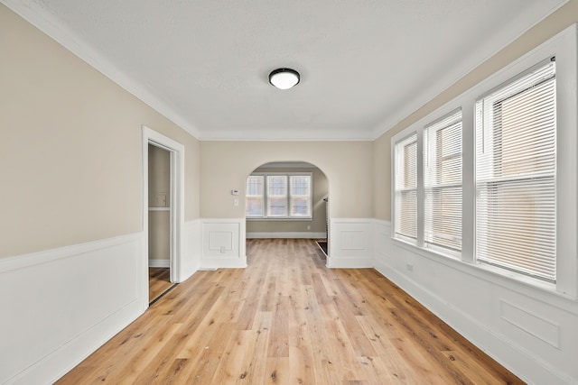 empty room with crown molding and light wood-type flooring