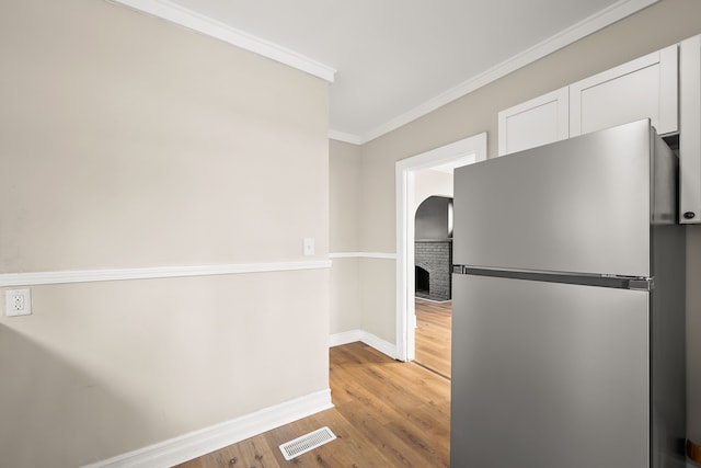 kitchen featuring crown molding, stainless steel fridge, light hardwood / wood-style floors, and white cabinets