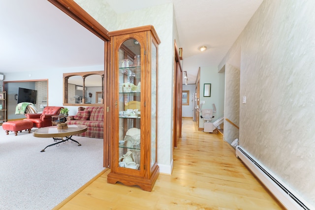 corridor with a baseboard radiator and wood-type flooring