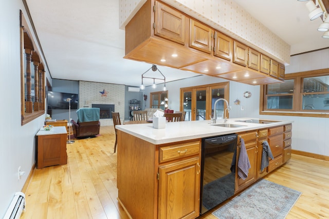 kitchen with a kitchen island with sink, black dishwasher, a fireplace, light hardwood / wood-style floors, and a baseboard radiator