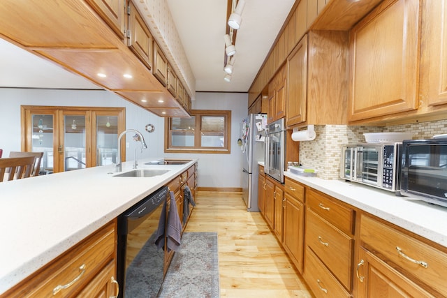 kitchen with sink, stainless steel appliances, track lighting, light hardwood / wood-style floors, and decorative backsplash