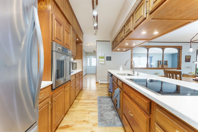 kitchen featuring sink, light wood-type flooring, track lighting, appliances with stainless steel finishes, and pendant lighting